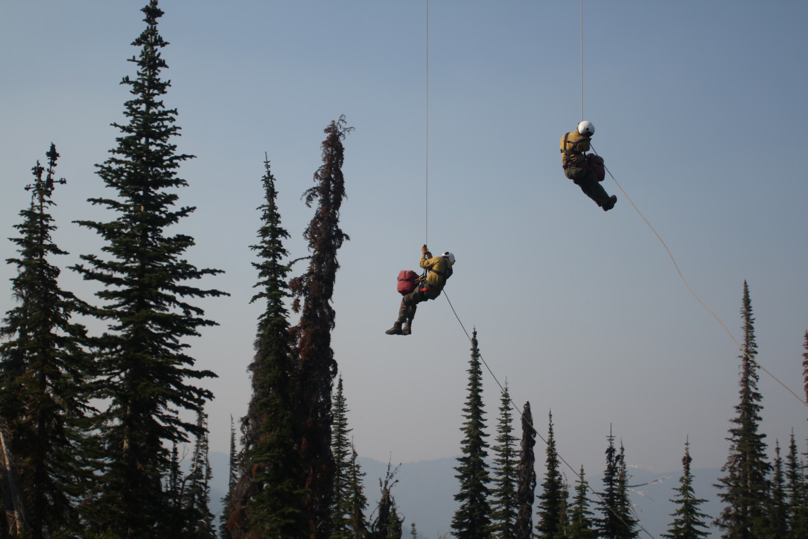 North Idaho heli-rappellers descend on ropes into remote forest terrain during helicopter rappel operations for wildland fire initial attack.