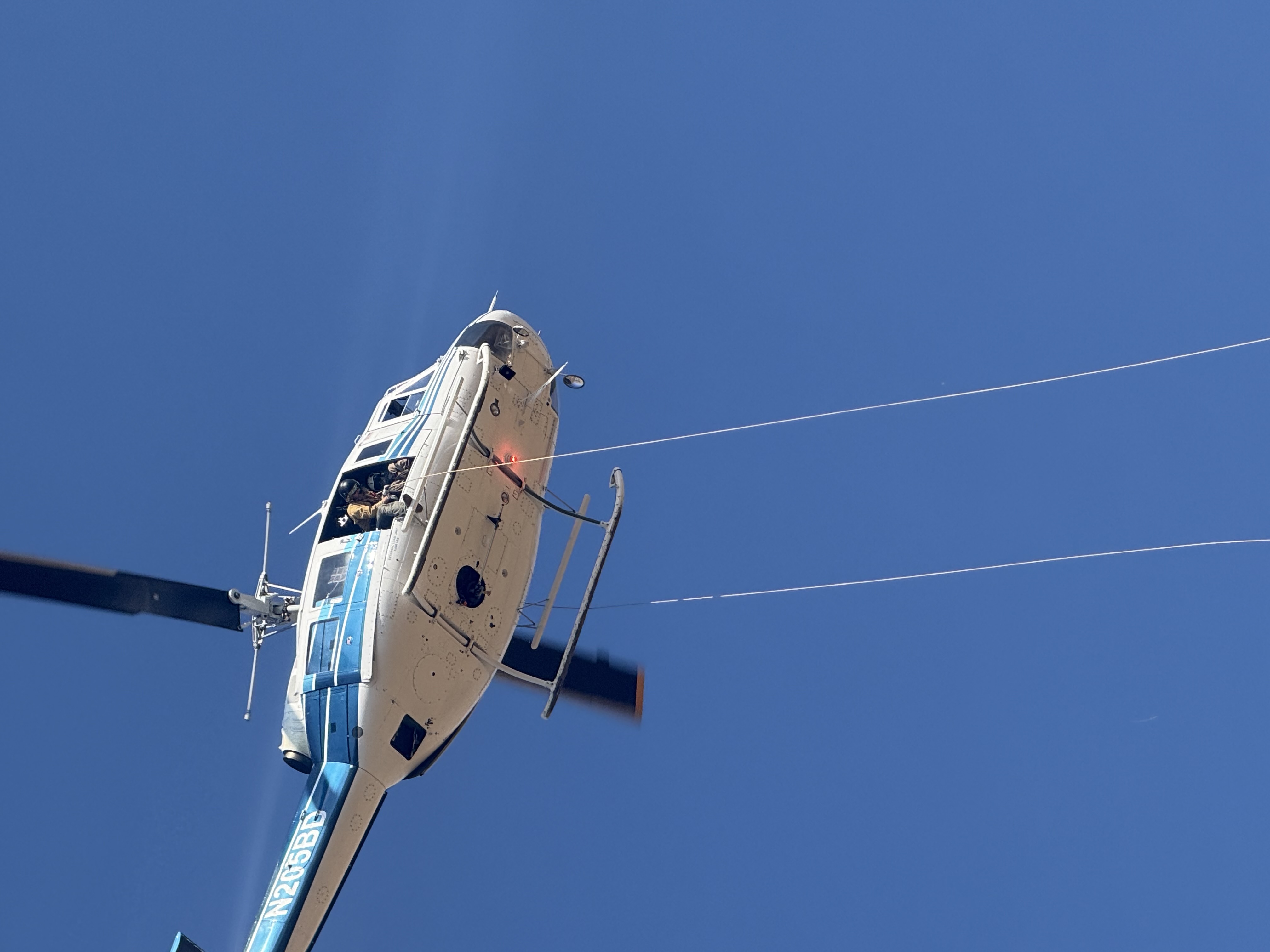 North Idaho Rappellers deploy rappel ropes from a helicopter during wildland fire operations, preparing to insert firefighters into remote terrain.