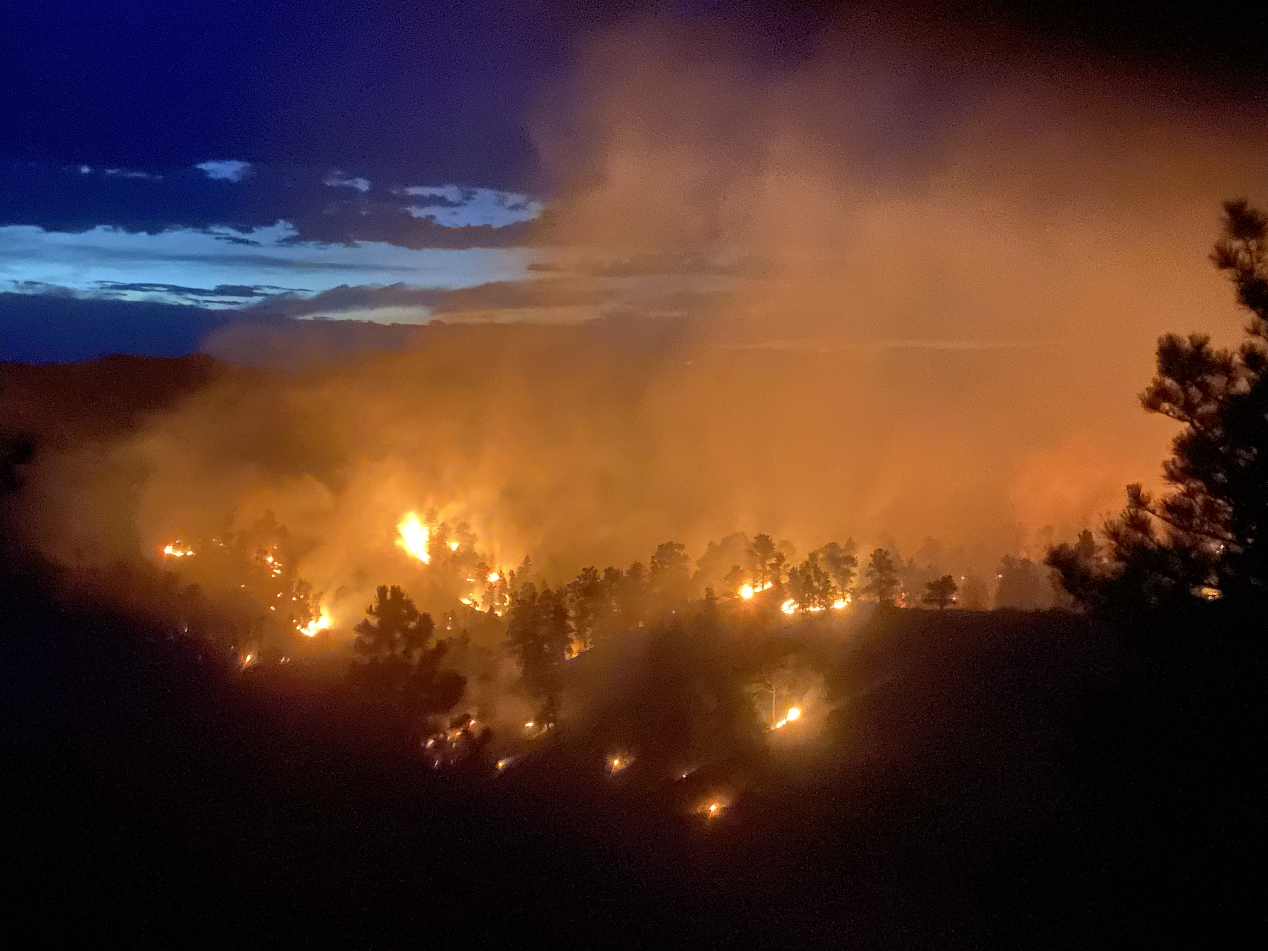 Nighttime wildfire behavior intensifies in timber, highlighting the conditions wildland firefighters can face on remote initial attack assignments.
