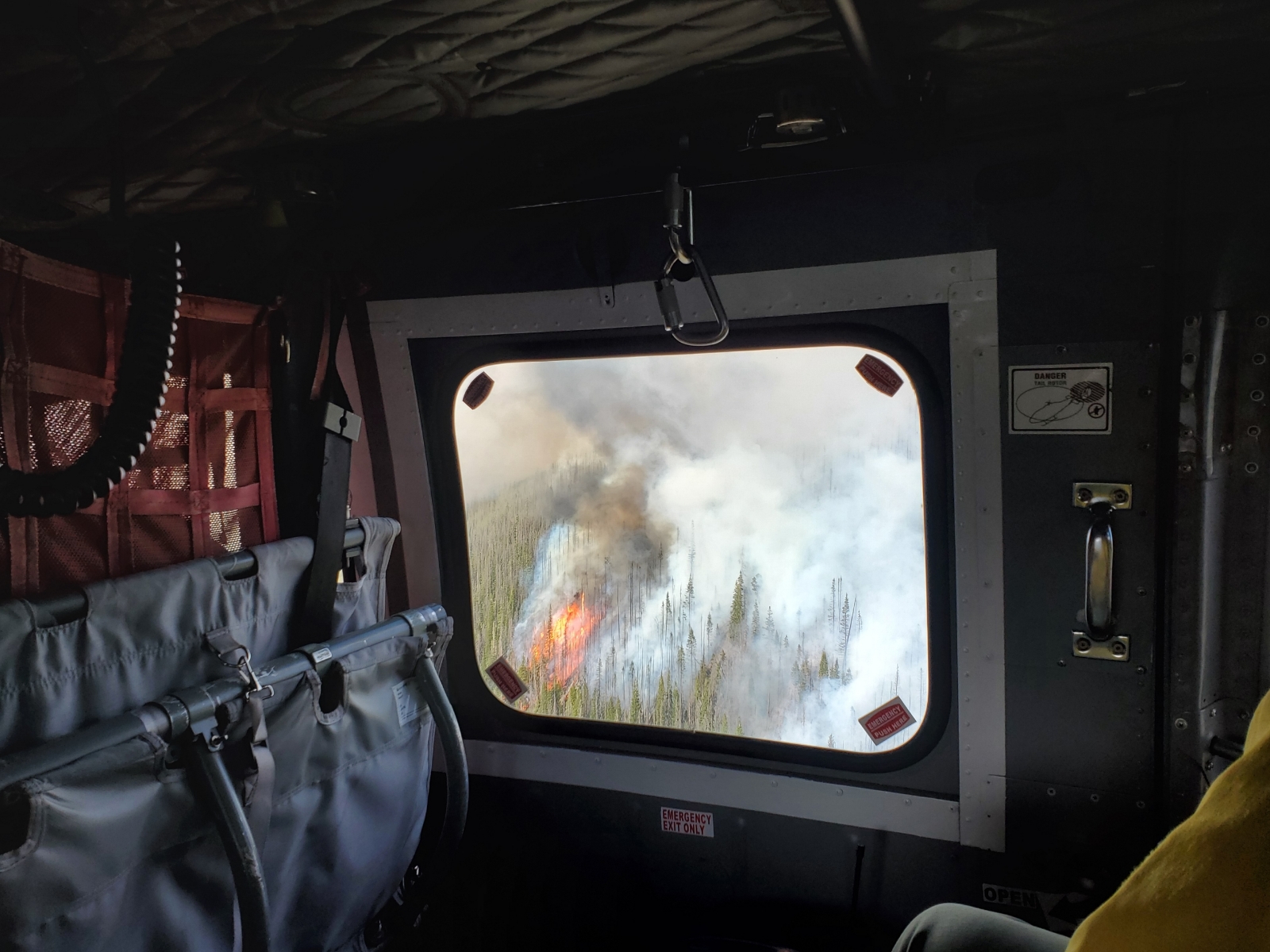 From inside the helicopter, an active wildfire comes into view below—an aerial perspective crews use to assess fire behavior and terrain before insertion.