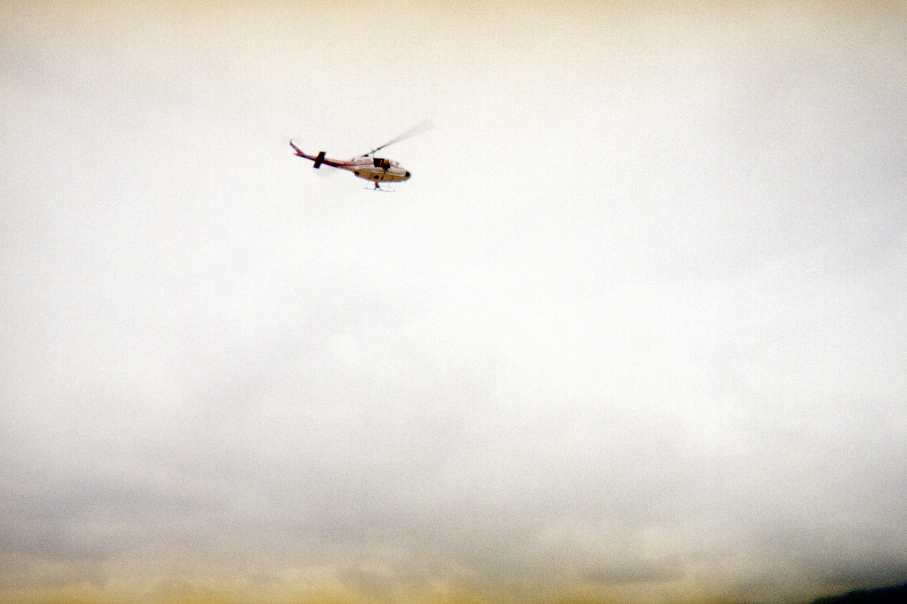A rappel helicopter moves through smoky skies en route to remote wildland fire operations.