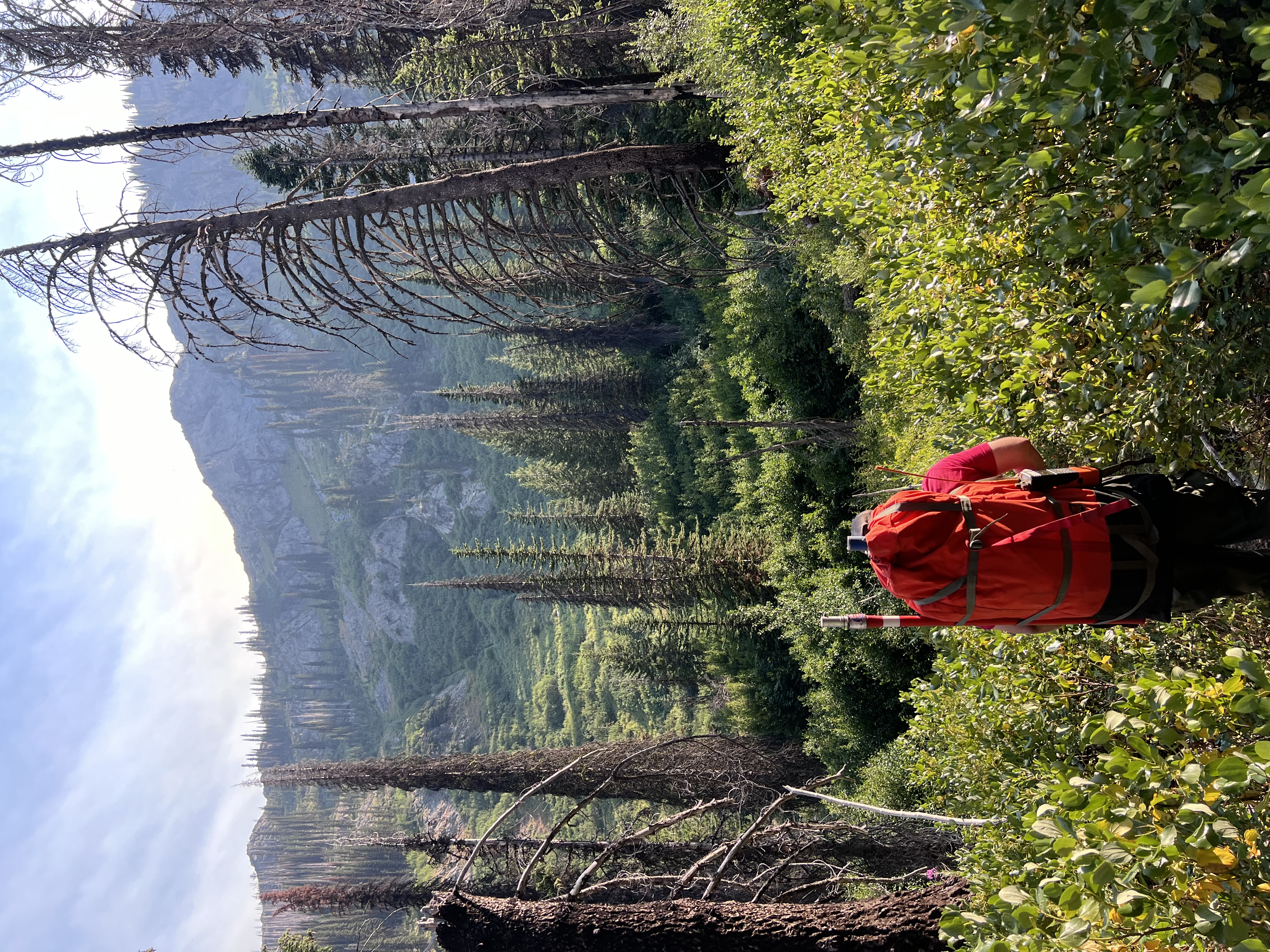 A heli-rappeller carries a full pack through steep Idaho backcountry, highlighting the rugged packouts that often follow remote wildfire assignments.